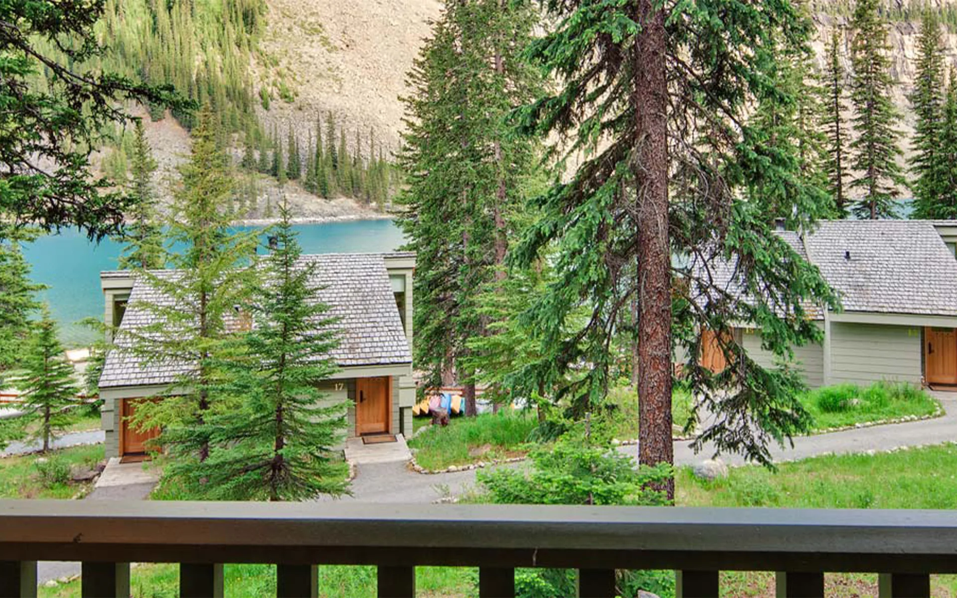 A scenic path winding through cozy cabins at Moraine Lake Lodge, surrounded by lush greenery and stunning mountain views. Guests enjoy a peaceful stroll in the heart of Banff National Park, immersed in nature’s beauty.