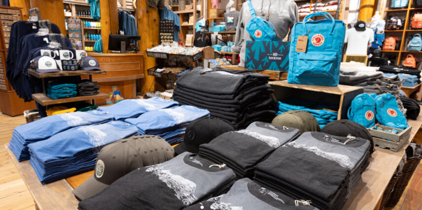 The Moraine Lake Trading Post, showcasing a variety of outdoor gear including t-shirts, bags, and other merchandise, with a rustic and inviting atmosphere.