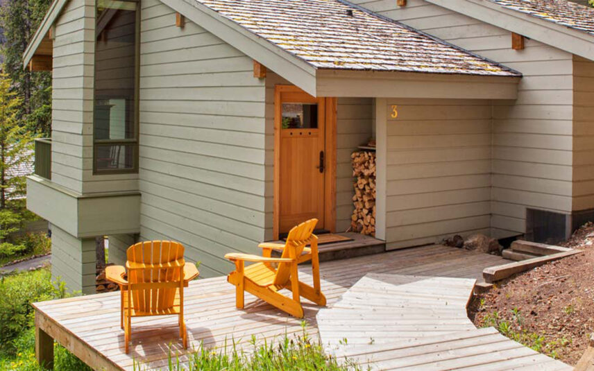 Image of yellow chairs sat in front of Moraine Lake lodge cabins overlooking the lake.