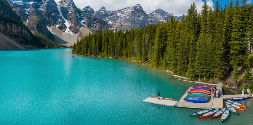 An instructor guiding a group of people at the canoe dock on Moraine Lake, preparing them for a canoeing adventure on the tranquil waters with stunning mountain views.